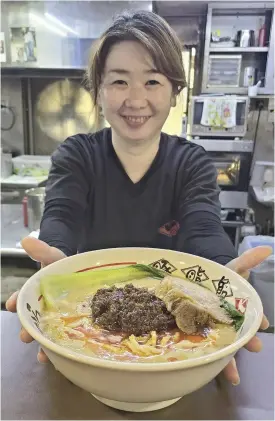  ?? The Yomiuri Shimbun ?? Rie Hasegawa holds out a bowl of Chibakara’s tantanmen spicy noodle dish in Ichihara, Chiba Prefecture.