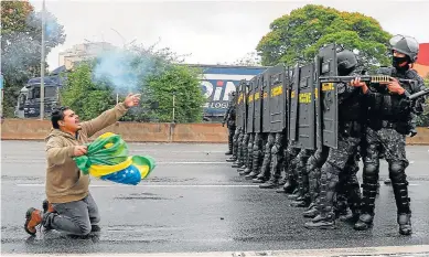  ?? MIGUEL SCHINCARIO­L/AFP ?? Un camionero grita delante de un grupo de policías preparados para disolver el bloqueo.