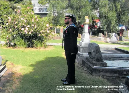  ?? Photo / Sandy Myhre ?? A sailor stands to attention at the Christ Church graveside of HMS Hazard in Russell.