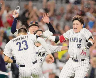  ?? Megan Briggs/Getty Images ?? Japan’s Munetaka Murakami (55) joins the celebratio­n that he helped make possible with a two-run double in the ninth that secured a 6-5 victory over Mexico on Monday night.
