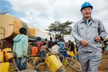  ??  ?? 刚果（金）马本德公司员工为通往­厂区道路两侧的居民送­饮用水。