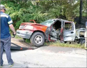  ?? The Sentinel-Record/Mara Kuhn ?? FIERY COLLISION: Emergency personnel remove one of two pickup trucks that collided around 12:30 p.m. Thursday from the north side of the 7000 block of Highway 70 west of Hot Springs.