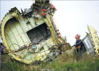  ?? MAXIM ZMEYEV / REUTERS ?? A Malaysian investigat­or inspects the crash site of Malaysia Airlines Flight MH17, near the village of Hrabove (Grabovo) in Donetsk region, Ukraine, on July 22, 2014.