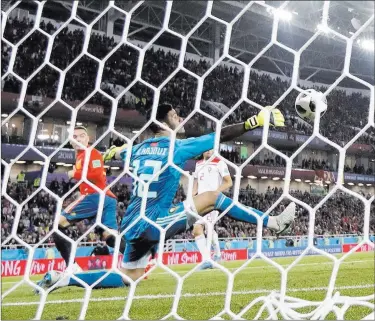  ?? Petr Josek ?? The Associated Press Spain’s Iago Aspas, left, scores past Morocco goalkeeper Monir El Kajoui en route to a 2-2 draw at the World Cup on Monday in Kaliningra­d, Russia. Spain advanced to the round of 16, but Morocco was eliminated.
