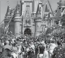  ?? JOE BURBANK/ORLANDO SENTINEL/AP PHOTO ?? In this March 12 file photo, a crowd is shown along Main Street USA in front of Cinderella Castle in the Magic Kingdom at Walt Disney World in Lake Buena Vista, Fla.