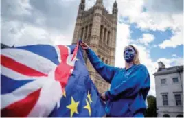  ??  ?? A Pro-European Union protester holds Union and European flags in front of the Victoria Tower at The Palace of Westminste­r in central London yesterday, ahead of a rally to warn about the terms of Brexit, by EU nationals in Britain and UK nationals in...