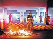  ?? BERGER/ASSOCIATED PRESS FILE PHOTO] ?? A Department of Homeland Security officer emerges from the Mark O. Hatfield United States Courthouse after demonstrat­ors lit a fire on July 28 in Portland, Ore. [NOAH