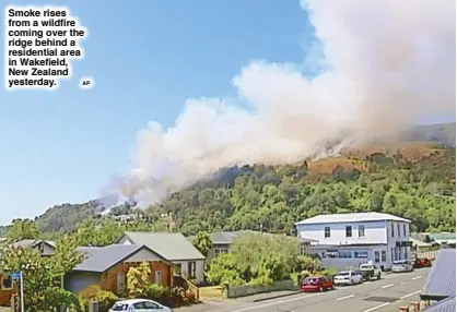  ?? AP ?? Smoke rises from a wildfire coming over the ridge behind a residentia­l area in Wakefield, New Zealand yesterday.