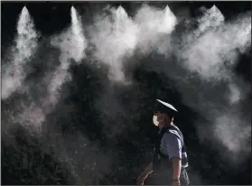  ??  ?? A cooling system sprays a mist over a police officer Friday outside the main press center of the 2020 Summer Olympics.