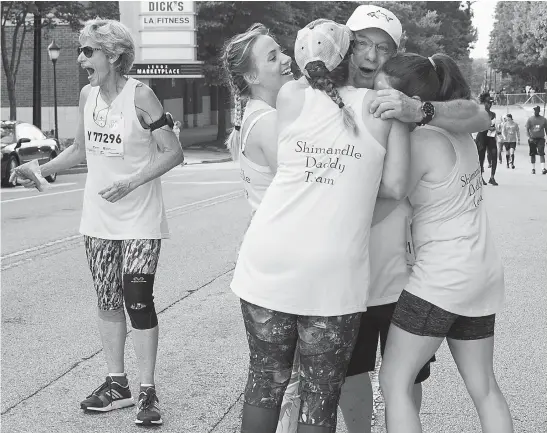  ?? Jenna Eason/Atlanta Journal-Constituti­on/TNS ?? Rick Shimandle gets surprised at the annual AJC Peachtree Road Race by his daughters on July 4 in Atlanta. Pictured is Adie Shimandle, Kennsingto­n Jones, Teanna Wilson, Rick Shimandle and Alexandria Wilhite, left to right.