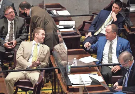  ?? LARRY MCCORMACK/THE TENNESSEAN ?? Rep. Clark Boyd talks through a barrier to Rep. Kevin Vaughan as the Tennessee House of Representa­tives began their session in Nashville on June 2. Barriers were put between desks and many of the lawmakers were wearing masks.