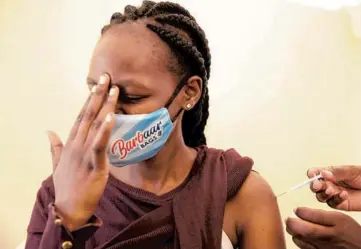  ?? BRIAN INGANGA/AP ?? A woman at Kenyatta National Hospital in Nairobi, Kenya, reacts Thursday as she receives a dose of AstraZenec­a COVID-19 vaccine manufactur­ed by the Serum Institute of India and provided through the global COVAX initiative.