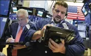  ?? RICHARD DREW / ASSOCIATED PRESS ?? Traders Edward McCarthy (left) and Michael Milano work on the floor of the New York Stock Exchange on Thursday as the Dow closed on its third straight record high.