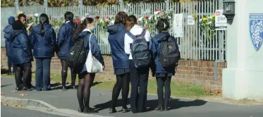  ?? | HENK KRUGER African News Agency (ANA) ?? LEARNERS from Rhenish Girls High gather outside the school to look at flowers in memory of a Grade 12 pupil who committed suicide.