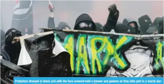  ?? — AFP ?? Protestors dressed in black and with the face covered hold a banner and gesture as they take part in a march during the annual May Day workers’ rally in Paris yesterday.