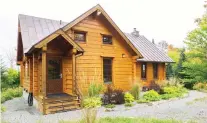  ??  ?? The moderate-sized structure is a rustic and elegant looking log home with Scandinavi­an touches, seen on the window frames outside.