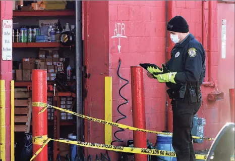 ?? Christian Abraham / Hearst Connecticu­t Media ?? An Orange police officer investigat­es a fatal shooting at Town Fair Tire in Orange on Saturday.