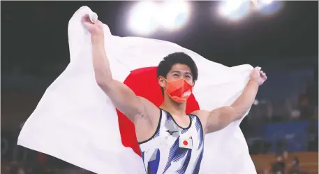  ?? LINDSEY WASSON/REUTERS ?? Daiki Hashimoto holds up a Japanese flag after winning the gold medal in men's all-around gymnastics at the Tokyo Olympics. Athletes from the host nation finished the Summer Games with 58 medals, including 27 gold, to set a new national record for Japan.