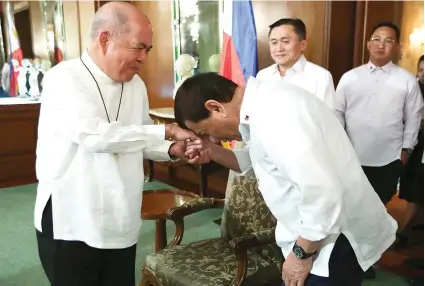  ?? /AP FOTO ?? ‘MANO PO’. President Rodrigo Duterte gestures to show respect to Archbishop Romulo Valles, president of the Catholic Bishops Conference of the Philippine­s, during their meeting in Malacañang.