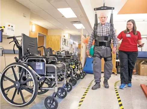  ??  ?? Robert Hayes, 87, dons the ZeroG Gait and Balance System for its maiden voyage with the assistance of physical therapist Annamarie Rosko on April 13 at Christus St. Vincent Regional Medical Center. The machine is a robotic body-weight support that...