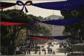  ?? (AP/Andreea Alexandru) ?? People cross the Martyrs of the Nation Boulevard, decorated with Albanian and EU flags as well as portraits of personalit­ies who made a contributi­on to the advancemen­t of the European Union on Monday in Tirana, Albania.