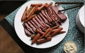  ??  ?? Baked corned beef, caramelize­d onions and carrots make this dish delicious and comforting. At dinnertime, a peppery maple glaze will make the whole dish shine.