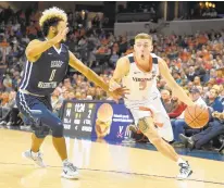  ?? MITCHELL LAYTON/GETTY IMAGES ?? Kyle Guy of the Virginia Cavaliers dribbles around Justin Mazzulla of the George Washington Colonials. Guy had 20 points for the Cavs, including 17 in a first half that ended with U.Va. ahead 42-17.