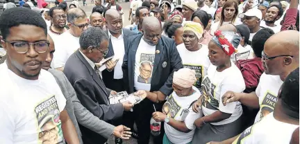  ?? /THULI DLAMINI ?? IFP leader Mangosuthu Buthelezi gives out voter registrati­on pamphlets to his supporters during the launch of his party’s voter registrati­on campaign at the Durban City Hall.