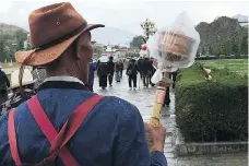  ??  ?? On a rainy morning, a devout Buddhist protects his prayer wheel with plastic while doing a kora, a clockwise walk around holy sites.