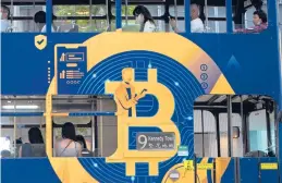  ?? KIN CHEUNG/AP ?? Bitcoin and Ethereum, the top two cryptocurr­encies also known for volatility, recently reached record-high values. Above, an ad for Bitcoin on a tram in Hong Kong.