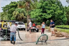  ?? RYAN TUCKER / ?? Loxahatche­e Groves residents Ryan Tucker, Jim Galloway and Ken Swindell, plus Councilwom­an Phillis Maniglia and Vice Mayor Todd McLendon, joined over Memorial Day weekend to help pump water off flooded roads into nearby canals.