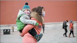  ?? ED JONES/GETTY-AFP ?? A mother and child wear face masks in pollution-heavy Beijing. China, which hosted the 2008 Olympics, is grappling with the long-term effects of air, water and soil pollution.