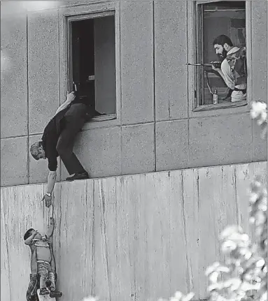  ?? [OMID VAHABZADEH/FARS NEWS AGENCY] ?? A man hands a child to a security guard from Iran’s parliament building after it was attacked Wednesday in Tehran.