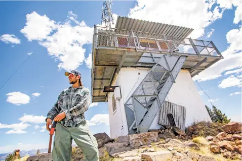  ?? PHOTOS BY GABRIELA CAMPOS/THE NEW MEXICAN ?? Sam Allen, a first-year lookout at the Jemez Ranger Station’s Cerro Pelado lookout tower, will man the tower through the fire season to monitor for smoke in the Santa Fe National Forest. He says he scans the horizon multiple times an hour.