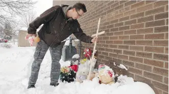  ?? IAN KUCERAK ?? Brad Chalmers places a cross on a memorial for a dead toddler at the back of the Good Shepherd Anglican Church in Edmonton on Sunday. The child’s body was discovered on Friday.
