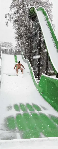  ?? Foto: Christian Wappler ?? Verkehrte Welt? Schnee im April: Schwimmmei­ster Jürgen Aicher nahm den Winter einbruch mit Humor und wagte sich im Inselbad auf die Rutsche.