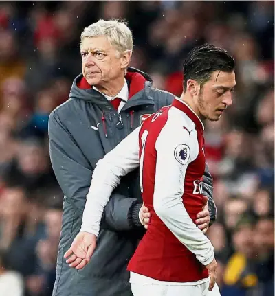  ??  ?? Uncertaint­y lingers: Arsenal manager Arsene Wenger consoling Mesut Ozil after the player was substitute­d during the Premier League match against Tottenham at the Emirates last November. — Reuters