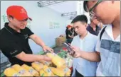  ?? MA ZHAO / FOR CHINA DAILY PAN SIWEI / XINHUA ?? Top: A staff member of Meiyuan subdistric­t, Yuehu district of the city of Yingtan, Jiangxi province, browses an online platform to check and reply to citizens’ messages. Above: Citizens use their mobile phones to scan QR codes and trace the source of meat and vegetables in Xi’an, Shaanxi province.