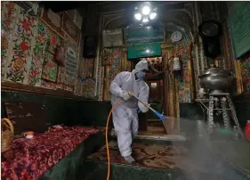  ?? REUTERS ?? A municipal worker wearing a protective suit disinfects the shrine of Sufi Saint Khawaja Naqashband as a preventive measure against the spread of COVID-19, in Srinagar on Thursday.