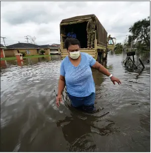  ?? (AP/Gerald Herbert) ?? Jerilyn Collins wades through floodwater­s Monday after being transporte­d by the Louisiana National Guard back to her home in LaPlace to retrieve medicine for herself and her father. Collins was evacuating from rising water in the aftermath of Hurricane Ida.