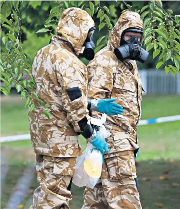  ??  ?? Men wearing hazardous material protective suits collect an item during a search of Queen Elizabeth Gardens in the centre of Salisbury