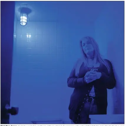  ?? (AP/David Goldman) ?? Misti Mann-France stands for a portrait in a bathroom at the laundromat she manages under a blue light installed to make it harder for drug users to find a vein in Huntington, W.Va. Hers was among several local businesses to install blue lights at the height of the city’s opioid crisis, when they would often find syringes left behind by drug users. “It was the only thing we could think of to do to help,” she said. “And it has helped tremendous­ly.” She said people have overdosed several times in the parking lot of their business, which includes the laundry and a video poker room. A local gas station chain and liquor store also switched to blue lights. “I wish there was a solution to the bigger problem,” she said. “There are so many out there on drugs, and it’s sad, it really is.”