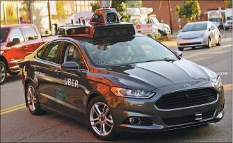  ?? JEFF SWENSEN/ GETTY IMAGES ?? An Uber driverless Ford Fusion drives down Smallman Street in Pittsburgh, Pennsylvan­ia.