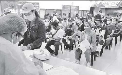  ?? GERRY LEE GORIT ?? Government personnel assist returning OFWs yesterday, as they register their personal details upon arrival at the Laguinding­an Airport in Misamis Oriental.