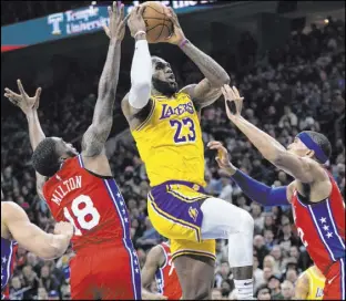  ?? Chris Szagola The Associated Press ?? Lakers forward LeBron James soars to the basket between 76ers guard Shake Milton and forward Tobias Harris in the first half of Los Angeles’ 108-91 loss Saturday night at the Wells Fargo Center.