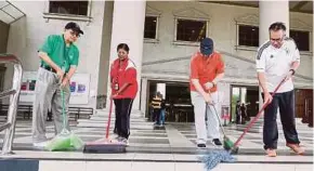  ??  ?? Kuala Lumpur Court Complex staff members mopping the floor.