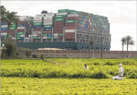  ?? MAHMOUD KHALED GETTY IMAGES ?? The MV Ever Given container ship is seen from a village in Egypt near the Suez Canal on Sunday. The ship ran aground in the canal on Tuesday and dredgers have been working on the port side of the ship in an attempt to remove sand and mud and dislodge the vessel.