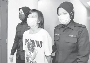  ?? — Gambar Bernama ?? TERTUDUH: Suri rumah Margaret Law (tengah) dan rakannya dihadapkan ke Mahkamah Majistret semalam atas pertuduhan membunuh suaminya di sebuah flat, Taman Daya, di Johor Bahru, pada 14 Julai lepas.