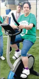  ??  ?? Gene Marchbanks, left, of Farmington, watches the time as Nancy Bolstad, also of the Farmington Senior Center, rides the stationary bike at the Senior Games on April 29. Participan­ts had to ride the bike for onehalf mile. Medals were given to the...