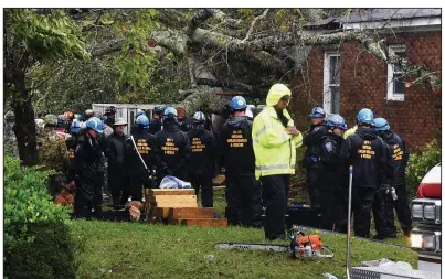  ?? AP/The News & Observer/CHUCK LIDDY ?? Rescue and emergency workers wait Friday to remove the bodies of a mother and child who were killed when a tree fell on their home in Wilmington, N.C., as Hurricane Florence made landfall. The father was transporte­d to a hospital with serious injuries.